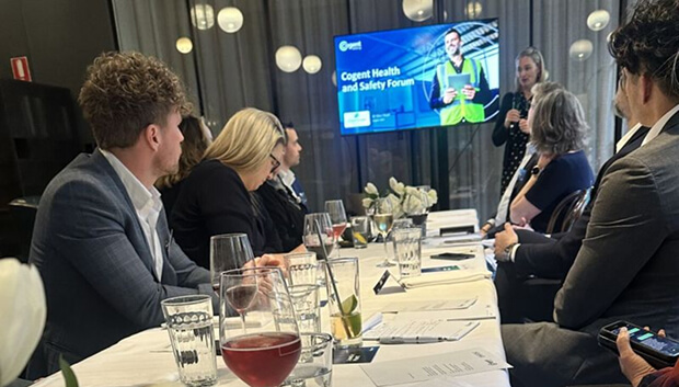 A group of people sit at business dinner, turned to the head of the table where they receive a presentation